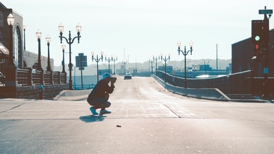 男子蹲在马路上拍照